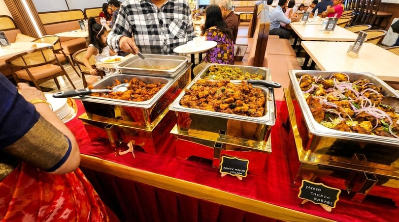 A buffet line with various chicken dishes, including kababs, in a restaurant setting.